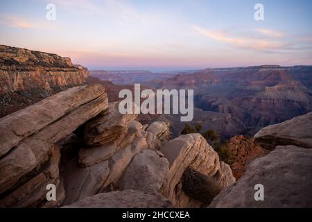 Affioramenti rocciosi lungo il South Kaibab Trail mentre l'Alba si spezza sul Grand Canyon Foto Stock