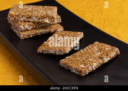 Dolci tradizionali indiani Mithai isolato su sfondo blu profondo per Makar Sankranti Lohri Gajak anche noto come Gur Gajjak Gazak Gachak Til Patti Foto Stock