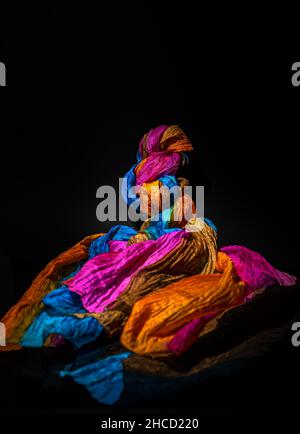 Sciarpa colorata su sfondo nero, pittura chiara Foto Stock