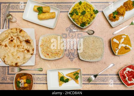 Set di piatti indiani con vari sapori curry, aglio naan e riso basmati con rotolo di formaggio Foto Stock