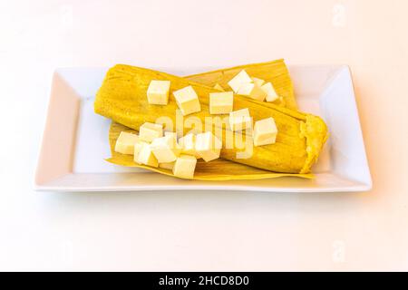 Humita con formaggio in pasta o pasta di mais leggermente condita, confezionata ed infine cotta o tostata nelle foglie di un orecchio di mais. Foto Stock