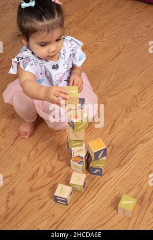 bambina di 17 mesi che fa torre di blocchi di legno Foto Stock