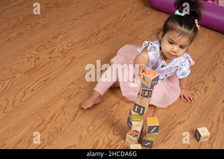 bambina di 17 mesi che fa torre di blocchi di legno Foto Stock