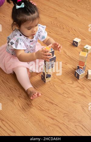 bambina di 17 mesi che fa torre di blocksbare in legno Foto Stock