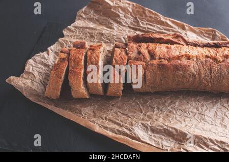 baguette di cereali tagliata a pezzi su carta pergamena su sfondo nero Foto Stock