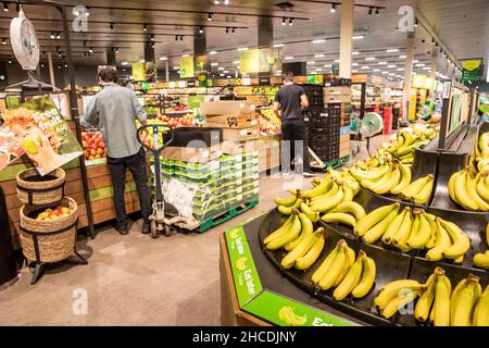 Scaffale impilatore indossare facemark durante il covid 19 rifocking zona frutta a Sydney supermercato, Australia Foto Stock