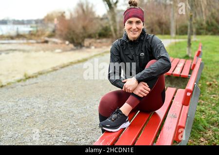 Lindau am Bodenseee, Germania. 16th Dic 2021. L'atleta Valeria Kleiner si trova su una panchina del parco sulla riva del lago di Costanza. Kleiner ha giocato nelle selezioni DFB, ha vinto i titoli, ha giocato nella Bundesliga di calcio femminile. Le lesioni hanno causato un cambiamento. Ora inizia come triatleta professionista. Credit: Felix Kästle/dpa/Alamy Live News Foto Stock