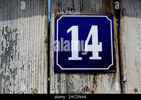 Numero 14 su un cartello smaltato attaccato ad una recinzione da giardino Foto Stock