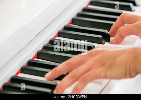 dita e mani di una donna che suona un pianoforte bianco Foto Stock