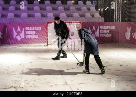 KIEV, UCRAINA - 26 DICEMBRE 2021 - la gente gioca l'hockey su ghiaccio ad un mercato di Natale, Kiev, capitale dell'Ucraina. Foto Stock