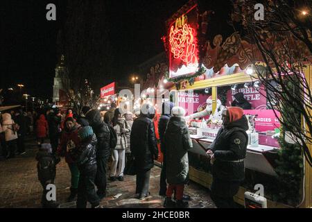 KIEV, UCRAINA - 26 DICEMBRE 2021 - la gente si accaparte fuori di una bancarella di cialda ad un mercato di Natale, Kyiv, capitale dell'Ucraina. Foto Stock