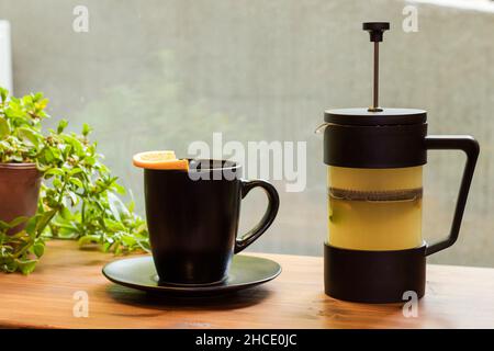 Tè verde con tazza arancione e nera, luce naturale Foto Stock