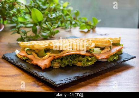 Waffle belgi con pesce e avocado sul piatto nero Foto Stock