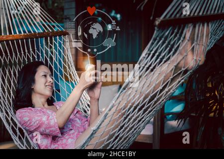 Donna asiatica felice che fa videochiamata sullo smartphone in vacanza. Foto Stock