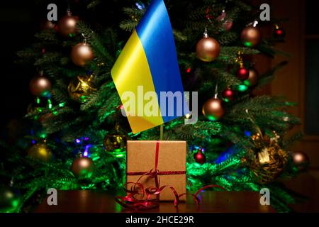 Bandiera Ucraina e scatola regalo sullo sfondo dell'albero di Natale Foto Stock