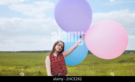 Ragazza felice con grandi palloncini multicolore in posa sul campo. Foto Stock