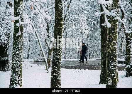 Le coppie anziane camminano insieme nel tempo invernale della neve. Alberi e terreno sono coperti di neve. Foto Stock