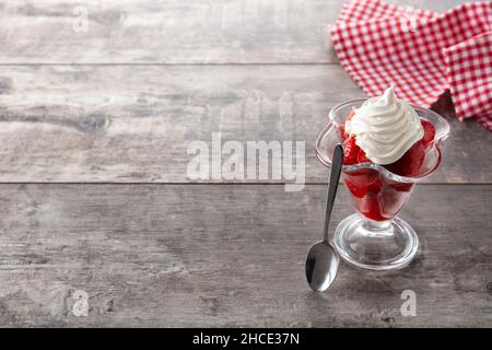 Fragole e panna montata in un bicchiere di gelato su un tavolo di legno Foto Stock