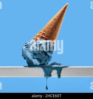 Appetitoso gelato blu fuso con cono di waffle posto su ringhiera bianca contro cielo nuvoloso brillante Foto Stock