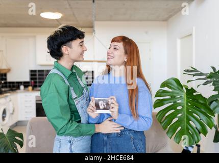 Donna enigmatica irriconoscibile in abito tradizionale creativo e capo vietnamita con illuminazione rossa in piedi in studio scuro su backgrou nero Foto Stock