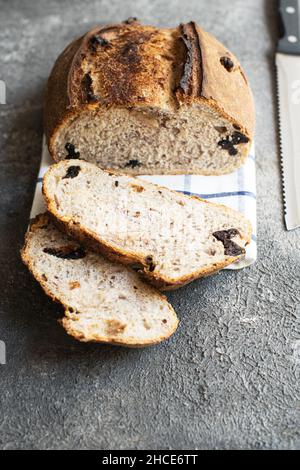 Pane fresco di pasta di origine affettato con albicocche secche e prugne secche su sfondo grigio. Primo piano. Foto Stock