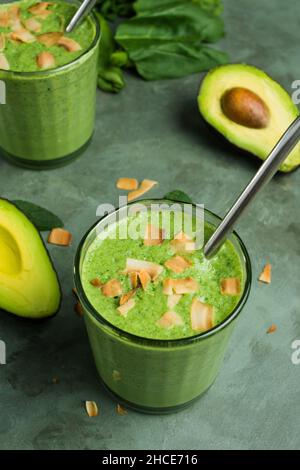 Bicchieri con frullato verde sano fatto con spinaci avocado e foglie di menta Foto Stock