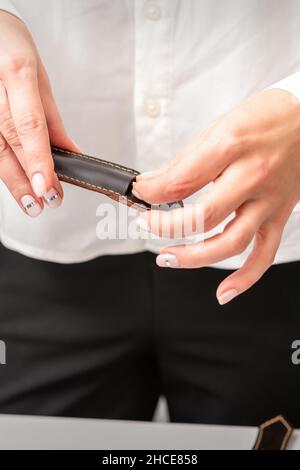 Mani e strumenti curati per una manicure. Mani di manicurista togliere lo strumento per un manicure dalla custodia in pelle in un salone unghie Foto Stock