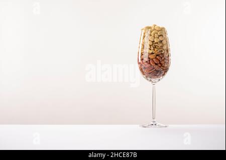 Vaso di vetro riempito con una varietà di nutrizione e snack sani e noci su uno sfondo bianco Foto Stock