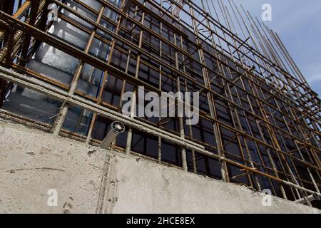 Struttura in cemento armato e gru a torre contro il cielo blu. Costruzione della fondazione. Struttura in calcestruzzo del cantiere. Processo di costruzione Foto Stock