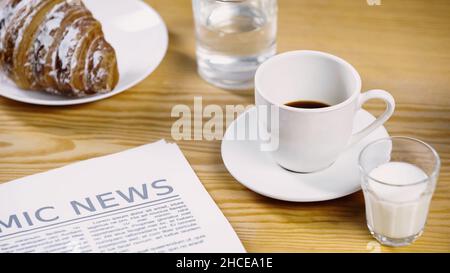 bicchiere di latte vicino a una tazza di caffè, giornale e croissant, immagine di scorta Foto Stock
