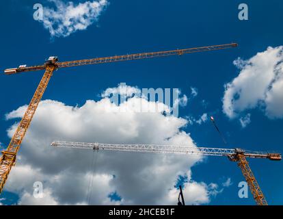Inquadratura ad angolo basso di alte gru su sfondo cielo nuvoloso Foto Stock