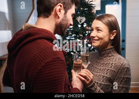 Coppia felice calice champagne flute durante il brindisi di Natale Foto Stock