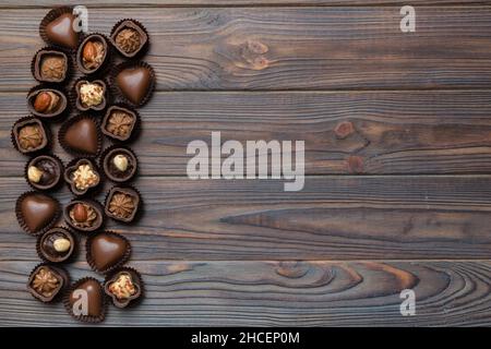 Diversi tipi di cioccolatini su un tavolo colorato da vicino. Vista dall'alto e disposizione piatta con spazio di copia. Foto Stock