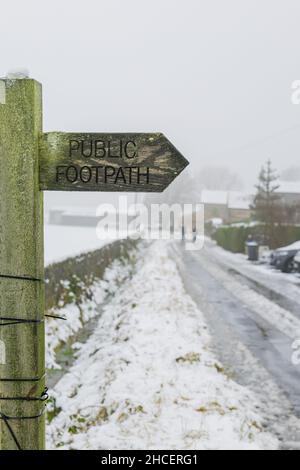 Un cartello per il sentiero pubblico su una corsia di campagna accanto a Otley Chevin, Yorkshire, durante la nevicata nell'inverno 2021. Foto Stock