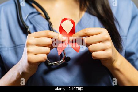 Nurse tenere il nastro rosso nelle mani per la giornata mondiale dell'AIDS Foto Stock