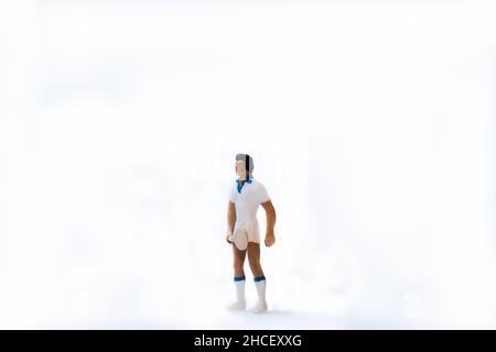 Atleta di tennis in miniatura con racchetta da tennis su sfondo bianco Foto Stock
