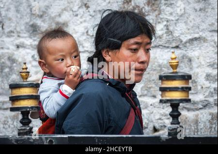 Pellegrini tibetani non identificati con abbigliamento tipico vicino al vecchio tempio di Jokhang a Lhasa, Tibet Foto Stock