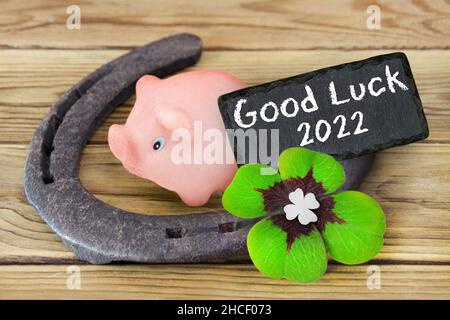Fortunati simboli marzapane piggy e trifoglio con buona fortuna 2022 su sfondo di legno Foto Stock