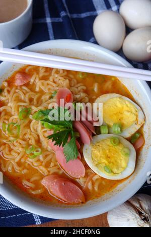 Foto della zuppa di noodle con condimenti come salsicce, uova e verdure Foto Stock