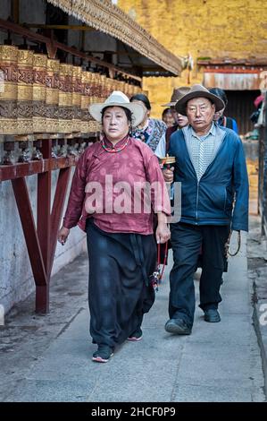 Pellegrini tibetani non identificati con abbigliamento tipico vicino al vecchio tempio di Jokhang a Lhasa, Tibet Foto Stock