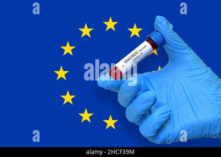 Il medico tiene la provetta per il test del sangue per il rilevamento della variante Omicron del virus Covid-19 con un risultato positivo sulla bandiera europea. Omicron Covi Foto Stock
