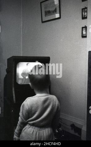 Fine del 1950s, storico, un ragazzino vicino ad un piccolo televisore dell'epoca che guarda un programma, Inghilterra, Regno Unito. Nel 1950, un televisore era un prodotto di lusso, con solo circa 350.000 famiglie britanniche in possesso di un televisore, ma alla fine del decennio quasi il 75% della popolazione aveva la televisione. Foto Stock