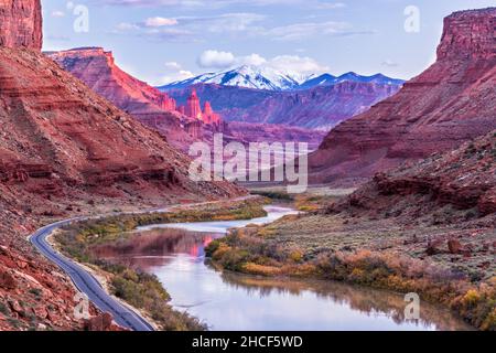 Il fiume Colorado si snoda verso Fisher Towers, che si illumina di rosa nella luce dell'autunno del tardo pomeriggio, con le montagne innevate di la SAL alle spalle. Foto Stock