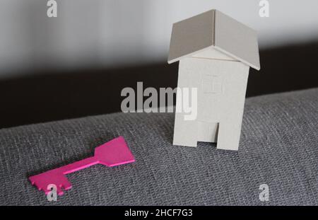 Casa in cartone con chiave rosa sul divano Foto Stock