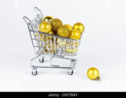 Carrello pieno di baubles di Natale, palla caduta vicino carrello. Concetto di consumismo di Capodanno. Foto Stock