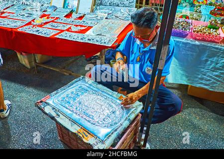 CHIANG mai, THAILANDIA - 4 MAGGIO 2019: L'argentiere crea un'impronta di Buddha ornata sul piatto in un laboratorio all'aperto d'argento, Sabato notte mercato a Wua Foto Stock