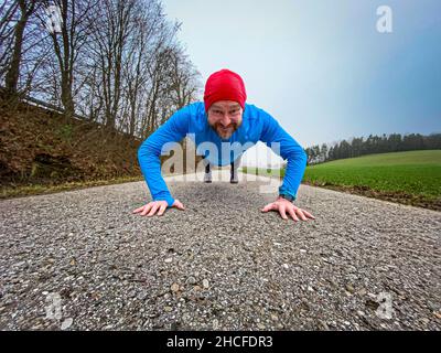 Uomo in corsa con cappellino rosso durante l'inverno Foto Stock