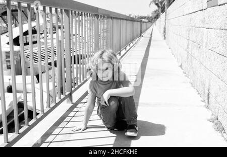 Ragazzo bambino prendere breve pausa hunkering giù sul lungomare, riposo Foto Stock