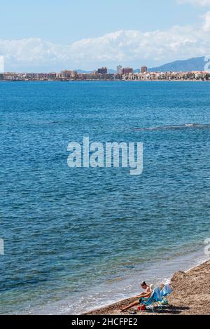 Coppia seduta sul mare blu mediterraneo a Isla Plana, con vista verso Puerto de Mazarron, Murcia, Spagna Foto Stock