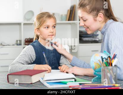 Madre controlli lezioni di scuola figlie Foto Stock